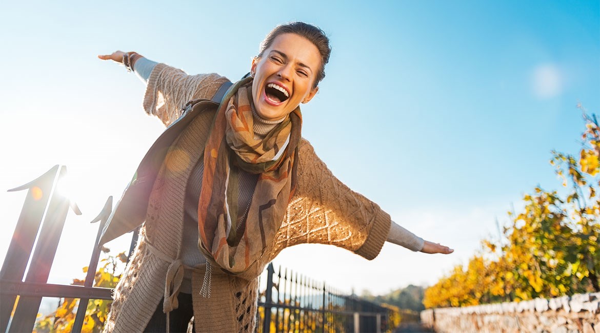 Image of young woman outside with arms spread as if she is flying.